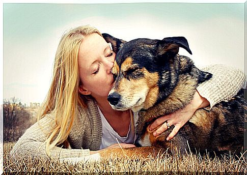 blonde girl hugs dog that has executed the command on the ground